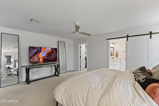 carpeted bedroom with a barn door, baseboards, visible vents, and ceiling fan