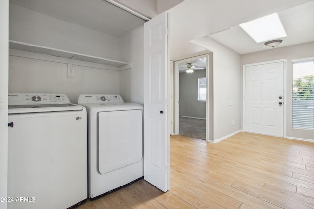 laundry area featuring light wood-type flooring, a skylight, ceiling fan, and washing machine and clothes dryer