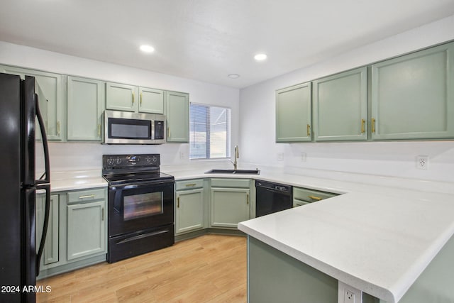 kitchen featuring sink, kitchen peninsula, light hardwood / wood-style floors, black appliances, and green cabinetry