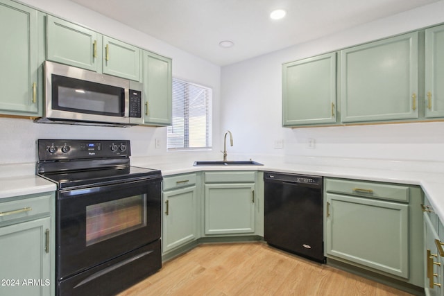 kitchen with light wood-type flooring, sink, green cabinets, and black appliances