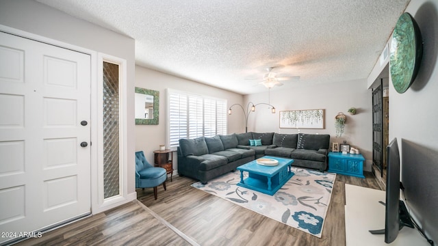 living room featuring ceiling fan, wood-type flooring, and a textured ceiling