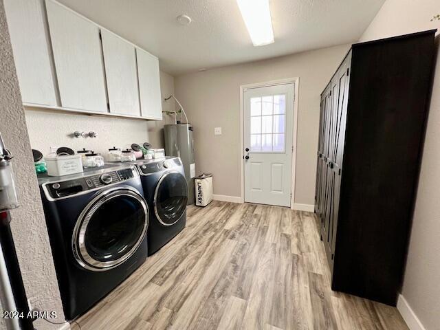 laundry area featuring washer and dryer, water heater, cabinets, and light wood-type flooring