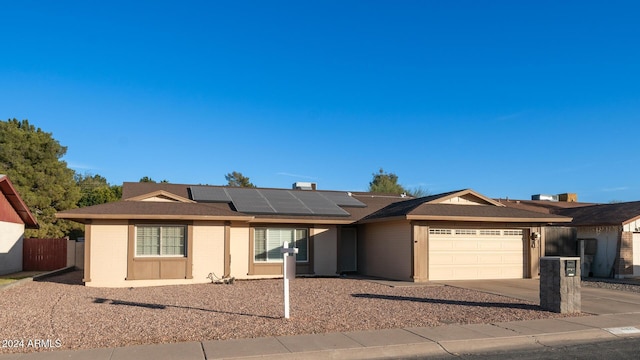 single story home with solar panels and a garage