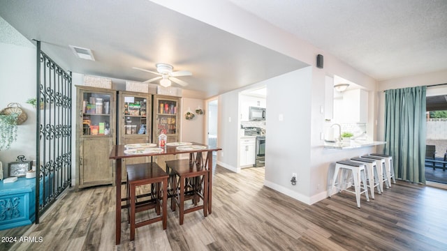 dining space with ceiling fan, hardwood / wood-style floors, a textured ceiling, and sink