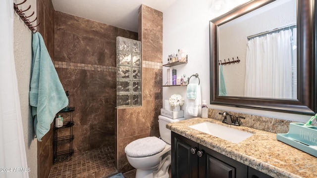 bathroom featuring a tile shower, vanity, and toilet