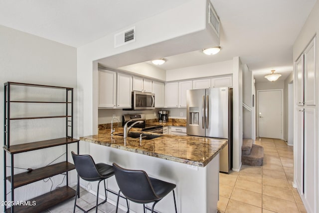 3440 E Southern Ave Unit 1042, Mesa, AZ 85204 - kitchen featuring appliances with stainless steel finishes, white cabinets, a peninsula, and dark stone countertops