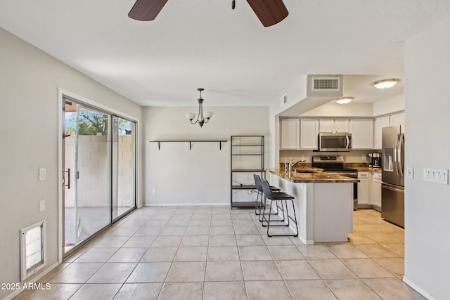 3440 E Southern Ave Unit 1042, Mesa, AZ 85204 - kitchen with stainless steel appliances, a ceiling fan, a peninsula, a kitchen bar, and white cabinetry