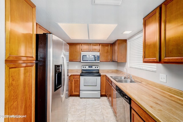 kitchen featuring appliances with stainless steel finishes, sink, and light tile patterned floors