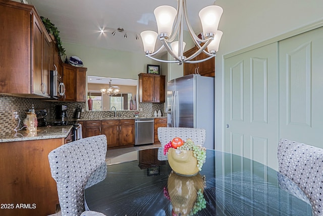 kitchen with decorative light fixtures, a notable chandelier, stainless steel appliances, brown cabinetry, and a sink