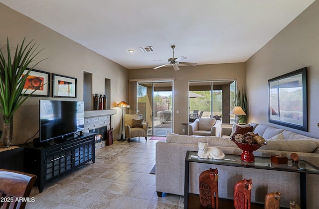 living area with light tile patterned floors, a glass covered fireplace, visible vents, and a ceiling fan