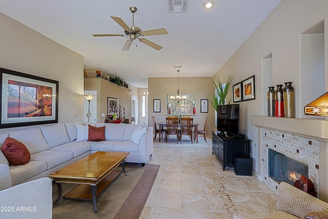 living room featuring light tile patterned floors, visible vents, a fireplace, and ceiling fan with notable chandelier