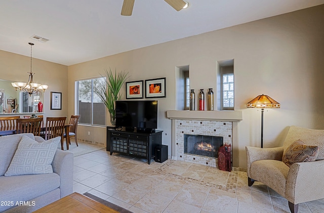 living room with visible vents, a tiled fireplace, and ceiling fan with notable chandelier