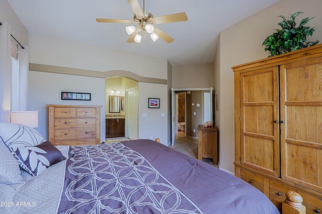 bedroom featuring ensuite bath, arched walkways, and a ceiling fan