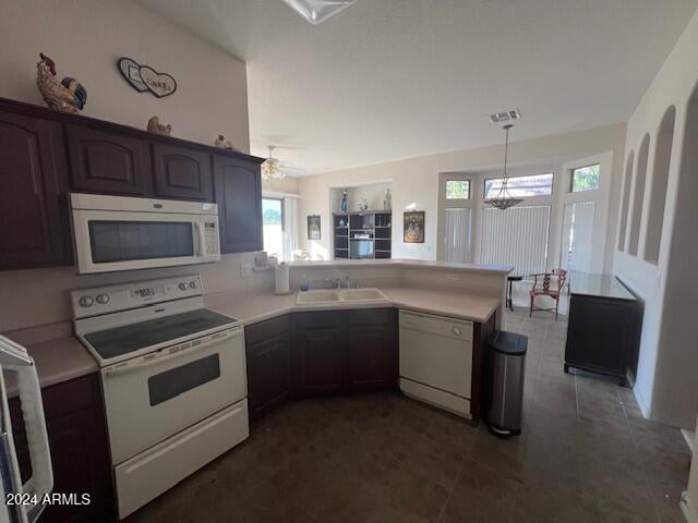 kitchen featuring sink, white appliances, dark brown cabinetry, decorative light fixtures, and kitchen peninsula