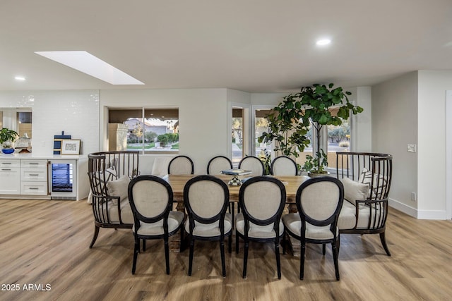 dining space with beverage cooler and light wood-type flooring