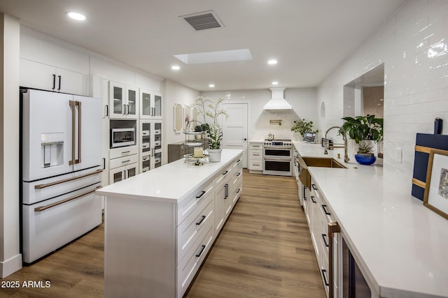 kitchen featuring stainless steel appliances, white cabinetry, a skylight, and a kitchen island