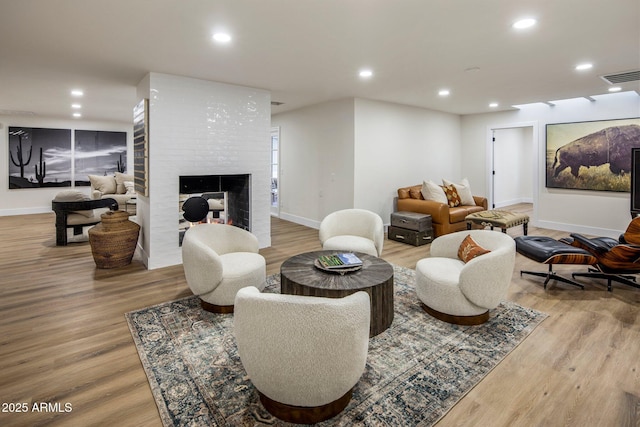 living room with a brick fireplace and hardwood / wood-style floors