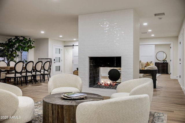 living room featuring light wood-type flooring, a multi sided fireplace, and a barn door