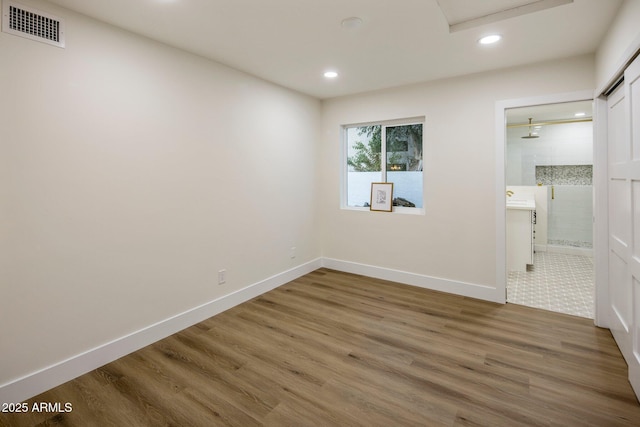 unfurnished bedroom with hardwood / wood-style floors, a closet, and ensuite bath