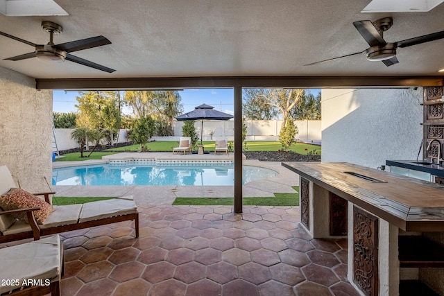 view of swimming pool featuring a bar, a patio, and ceiling fan