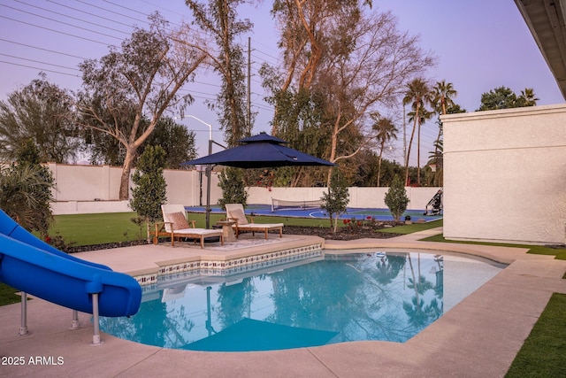 pool at dusk featuring a patio and a water slide