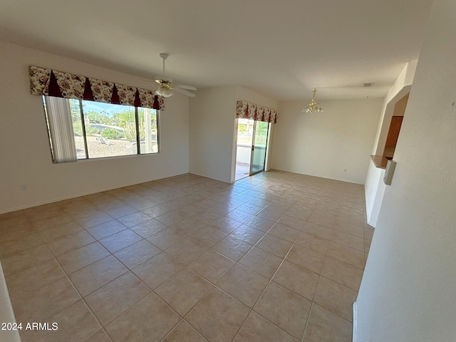 tiled spare room with ceiling fan with notable chandelier and plenty of natural light