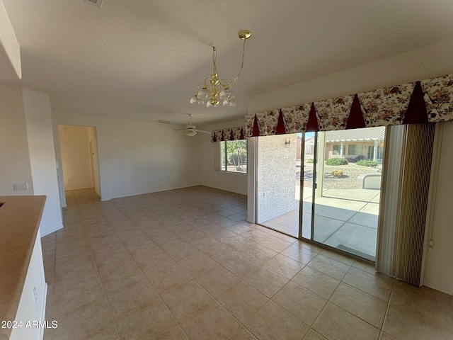 unfurnished dining area with light tile patterned flooring and ceiling fan with notable chandelier