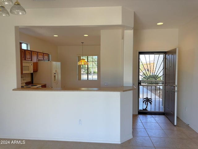 kitchen with light tile patterned flooring, hanging light fixtures, and white appliances