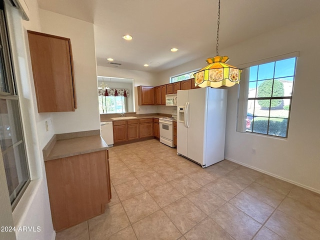 kitchen featuring hanging light fixtures, a wealth of natural light, sink, and white appliances