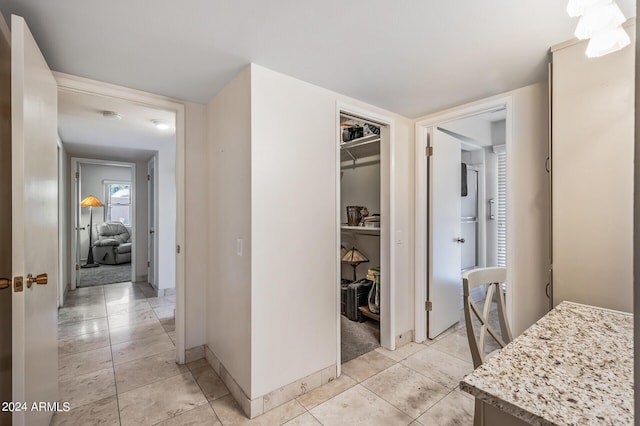 hall featuring light tile patterned floors and baseboards