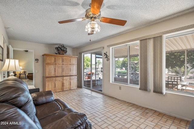 living area with brick floor, a textured ceiling, and a ceiling fan