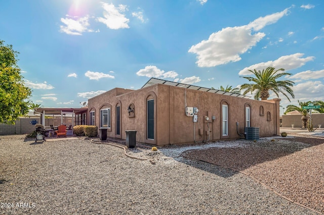 view of side of property with a patio, stucco siding, and central air condition unit