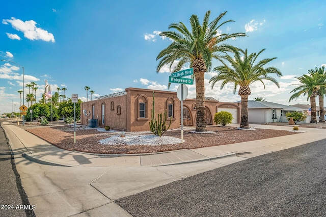 view of front of house with concrete driveway, an attached garage, and cooling unit