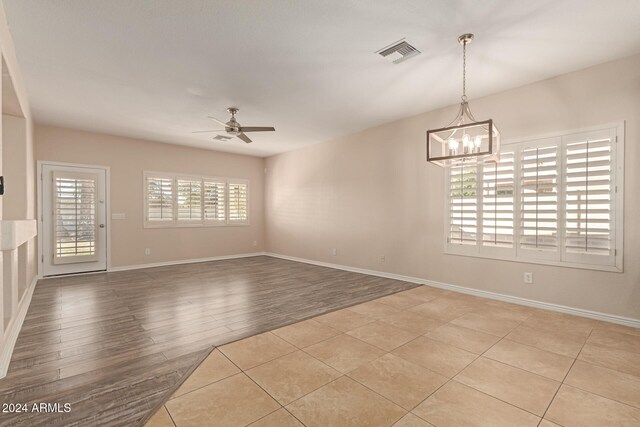 spare room featuring light hardwood / wood-style flooring and ceiling fan with notable chandelier