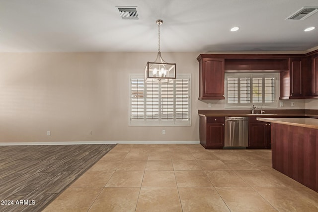 kitchen with pendant lighting, dishwasher, sink, light tile patterned floors, and a notable chandelier