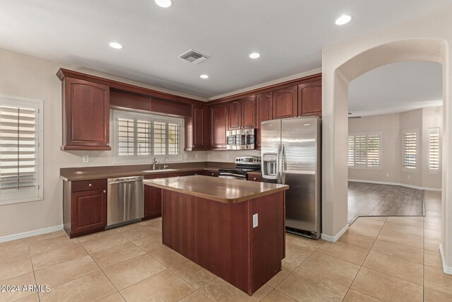 kitchen featuring sink, a kitchen island, stainless steel appliances, and light hardwood / wood-style floors