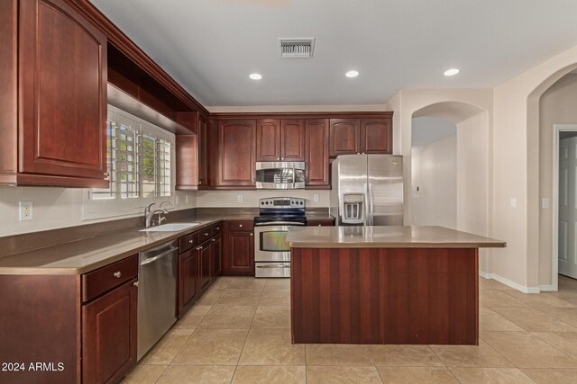 kitchen with light tile patterned flooring, sink, a kitchen island, and stainless steel appliances