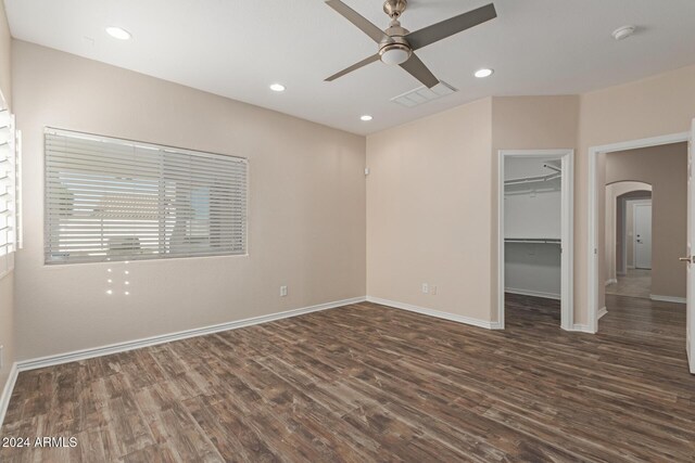 unfurnished bedroom with dark hardwood / wood-style flooring, a closet, a spacious closet, and ceiling fan