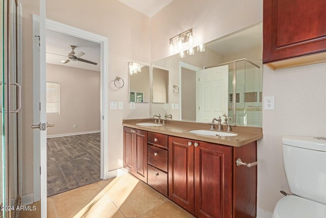 bathroom with tile patterned floors, vanity, ceiling fan, toilet, and a shower with shower door