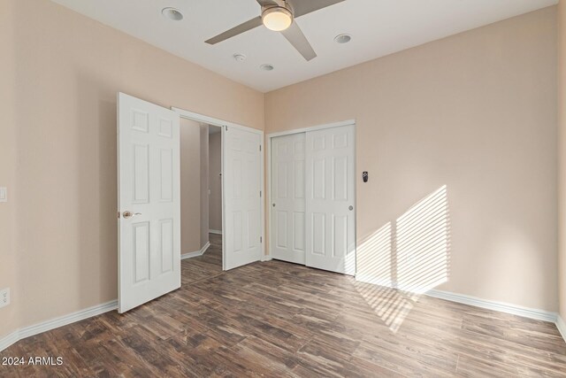 unfurnished bedroom with a closet, ceiling fan, and dark wood-type flooring