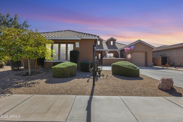 view of front of property with a garage, concrete driveway, a tiled roof, and stucco siding