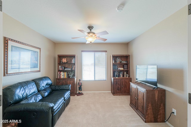 living room featuring ceiling fan, baseboards, and light colored carpet