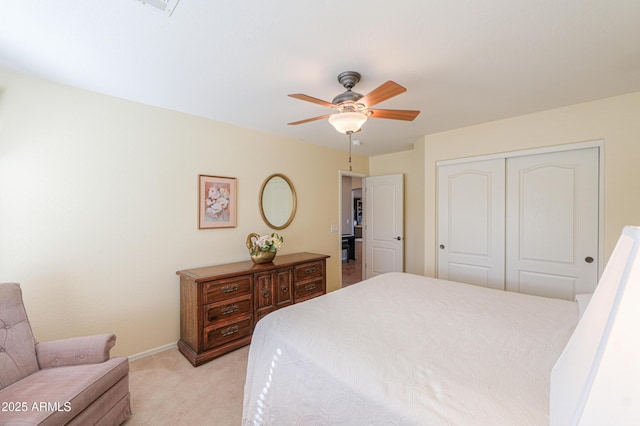 bedroom with a ceiling fan, a closet, light colored carpet, and baseboards