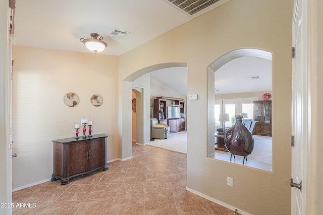 hallway featuring visible vents, arched walkways, and baseboards