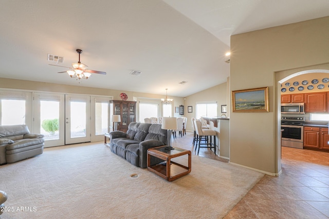 living area featuring light colored carpet, lofted ceiling, visible vents, and ceiling fan with notable chandelier