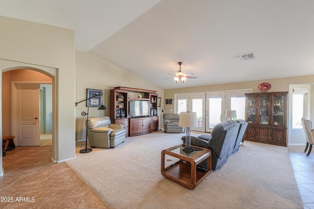 living area featuring visible vents, arched walkways, vaulted ceiling, and a wealth of natural light