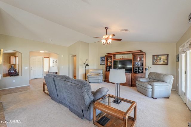 living room with lofted ceiling, visible vents, light carpet, and arched walkways