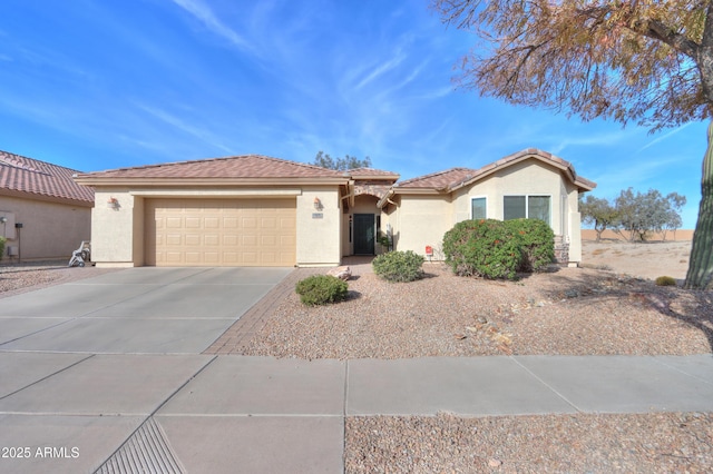 view of front of house featuring a garage, concrete driveway, a tiled roof, and stucco siding