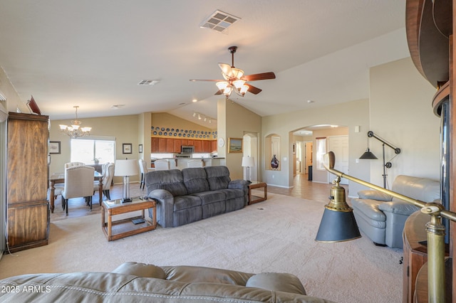 living area with visible vents, vaulted ceiling, arched walkways, and light colored carpet
