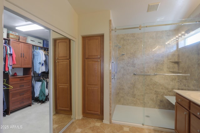bathroom featuring a shower stall, visible vents, a walk in closet, and vanity
